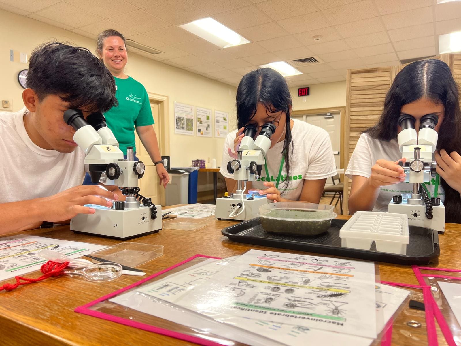 Image20250502101154 A group of people sitting around a table with microscopes.
